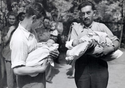 Two refugees born in flight from Poland were held by their proud fathers in Vienna. At all stages of their journey, they received JDC assistance. Their well-being would be looked after in the more stable environment of a "permanent" camp, with supplementary food, medical and child care services provided by JDC. Austria, c. 1946.